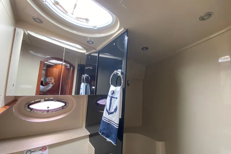 Yacht Photos Pics 2007 Cruisers Yachts 370 Express bathroom with porthole, mirror, and nautical-themed towel.