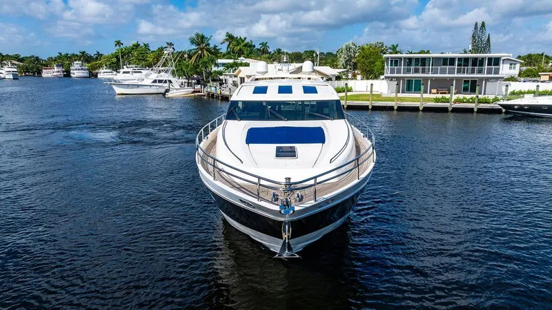  Yacht Photos Pics Luxury 2010 Princess V78 yacht on a serene waterway, surrounded by modern homes.