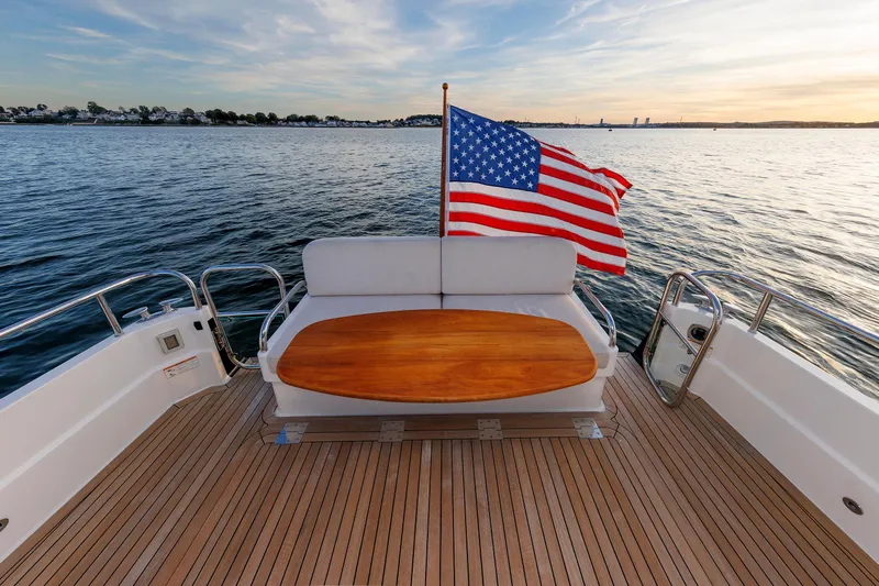  Yacht Photos Pics 2022 Sabre 38 SE yacht deck with American flag, wooden table, and scenic water view.