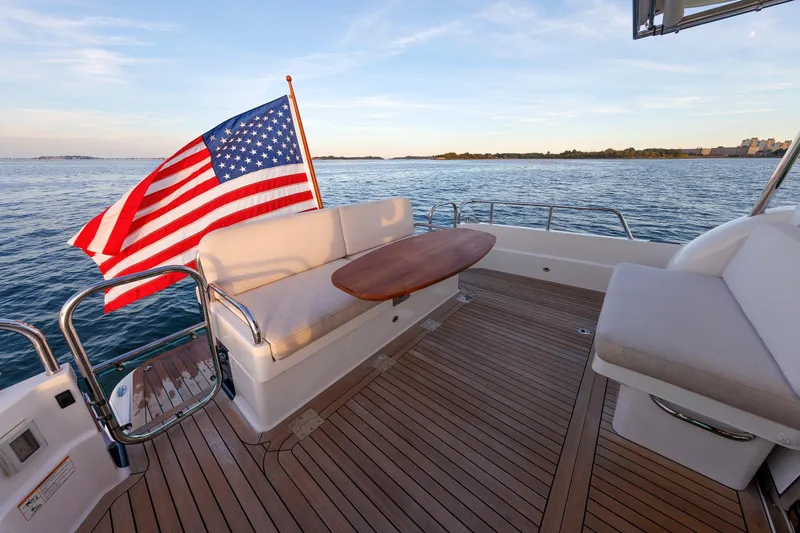  Yacht Photos Pics 2022 Sabre 38 SE yacht deck with American flag, wooden table, and ocean view.