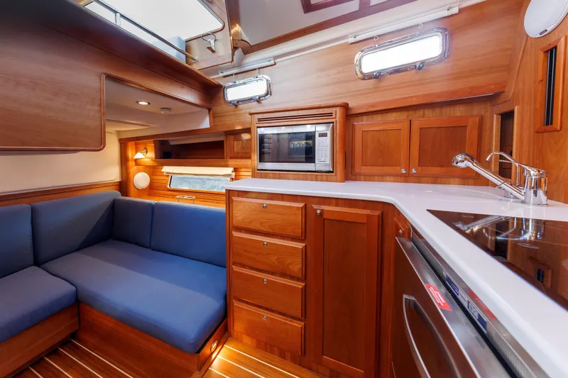  Yacht Photos Pics 2022 Sabre 38 SE yacht interior with wooden cabinetry, blue seating, and modern kitchen amenities.