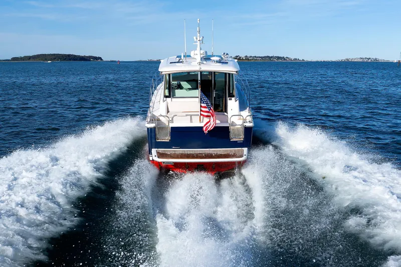  Yacht Photos Pics 2022 Sabre 38 SE yacht cruising on open water, rear view with American flag.