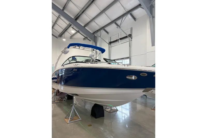  Yacht Photos Pics 2026 Regal LS6 Surf boat in showroom, blue and white design, elevated on stands.