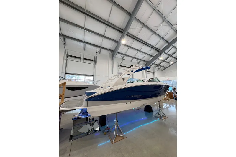  Yacht Photos Pics 2026 Regal LS6 Surf boat in showroom, blue and white design, elevated on stands.