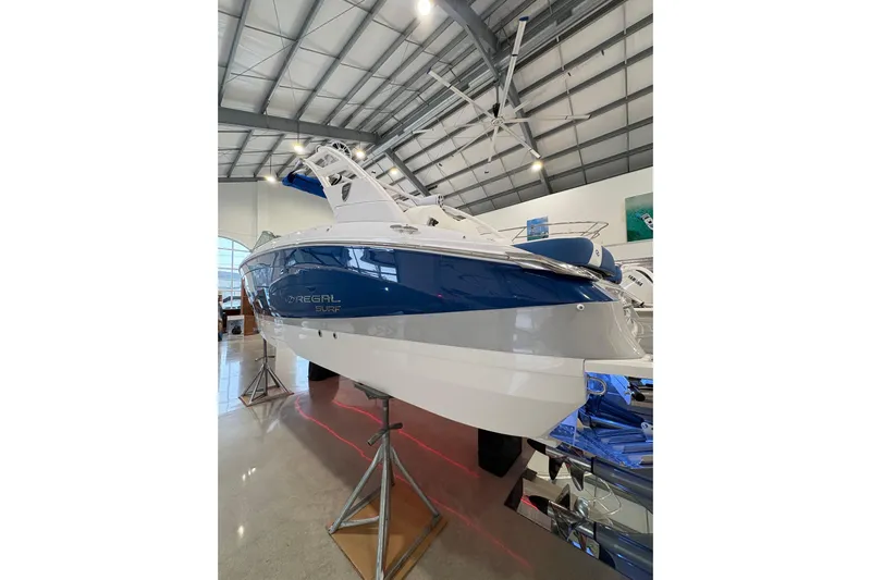  Yacht Photos Pics 2026 Regal LS6 Surf boat displayed in a showroom, featuring sleek blue and white design.