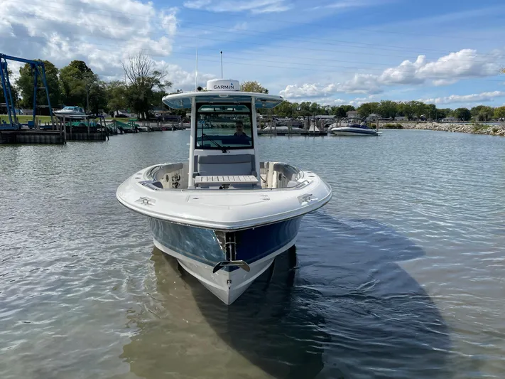  Yacht Photos Pics 2022 Boston Whaler 330 Outrage boat docked in calm waters under a blue sky.