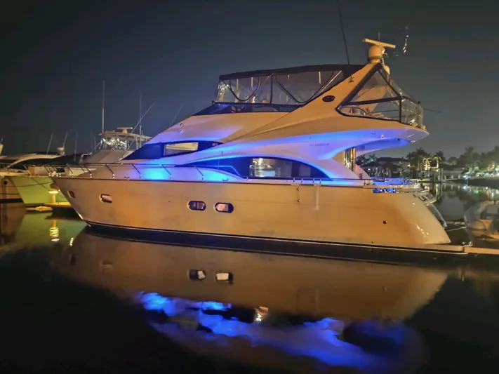 La Vida Loca Yacht Photos Pics 2004 Marquis 59 yacht illuminated at night with blue lights, docked in a marina.