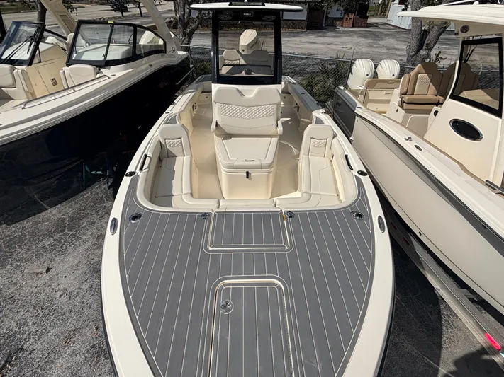  Yacht Photos Pics 2025 Scout 281 XSS boat with sleek design and spacious deck, docked alongside other boats.