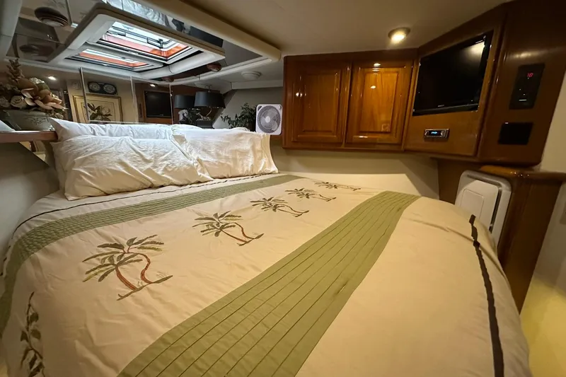 So Blessed Yacht Photos Pics Cozy bedroom in 1998 Viking 54 Motor Yacht with palm-themed bedding and wooden cabinetry.