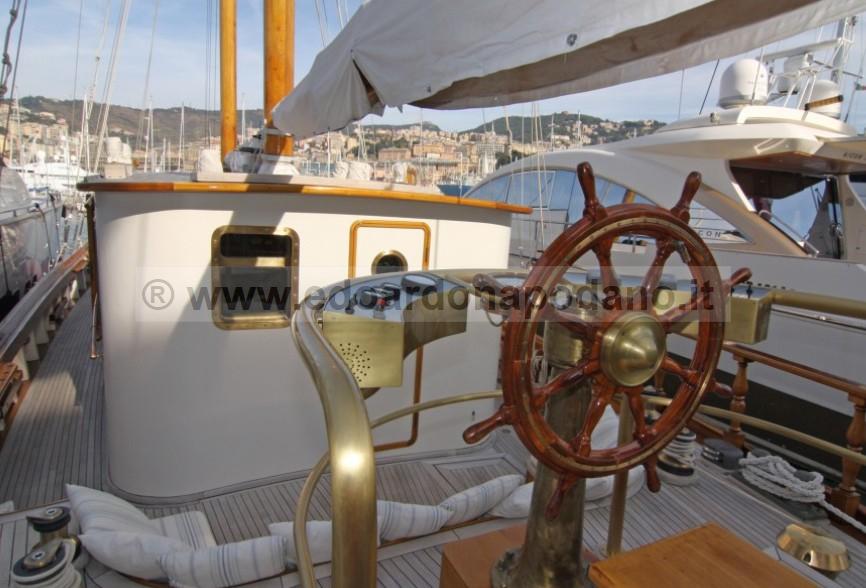 Wooden helm of a 1925 Codecasa schooner, docked in a marina.
