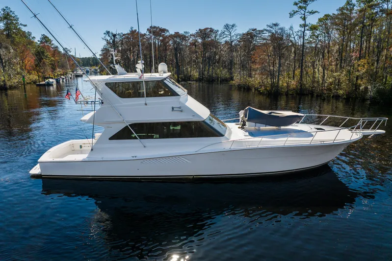 Marysea Yacht Photos Pics 1999 Viking 58 Convertible yacht cruising on a serene river with forested banks.