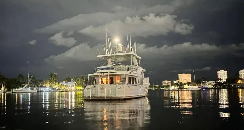 Beyond Capricorn 1 Yacht Photos Pics 2001 Nordhavn 57 yacht illuminated at night on calm waters, with cityscape background.