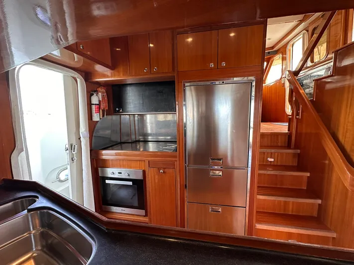 Beyond Capricorn 1 Yacht Photos Pics Interior of 2001 Nordhavn 57 yacht kitchen with stainless steel appliances and wooden cabinetry.