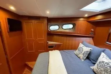 Oasis Yacht Photos Pics Luxurious cabin interior of 2024 Northwest 55 yacht with cozy bedding and elegant wood finish.