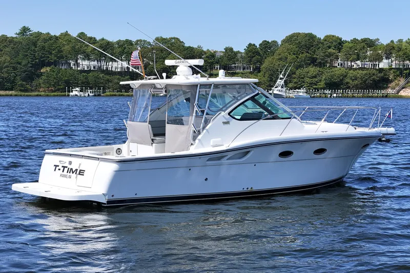 T-time Yacht Photos Pics 2006 Tiara 3200 Open yacht on calm water, surrounded by lush greenery.