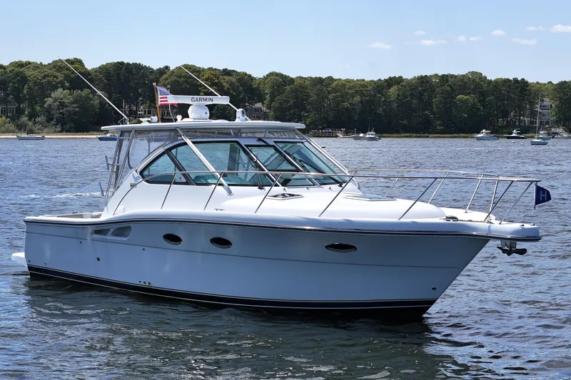 T-time Yacht Photos Pics 2006 Tiara 3200 Open yacht on calm water, surrounded by lush greenery.