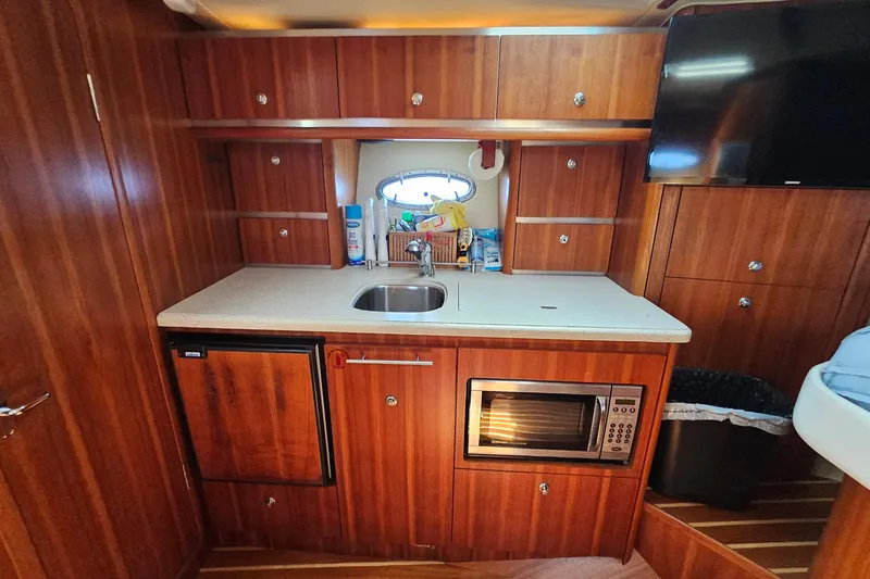 T-time Yacht Photos Pics 2006 Tiara 3200 Open yacht interior kitchen with wood cabinetry, sink, and microwave.