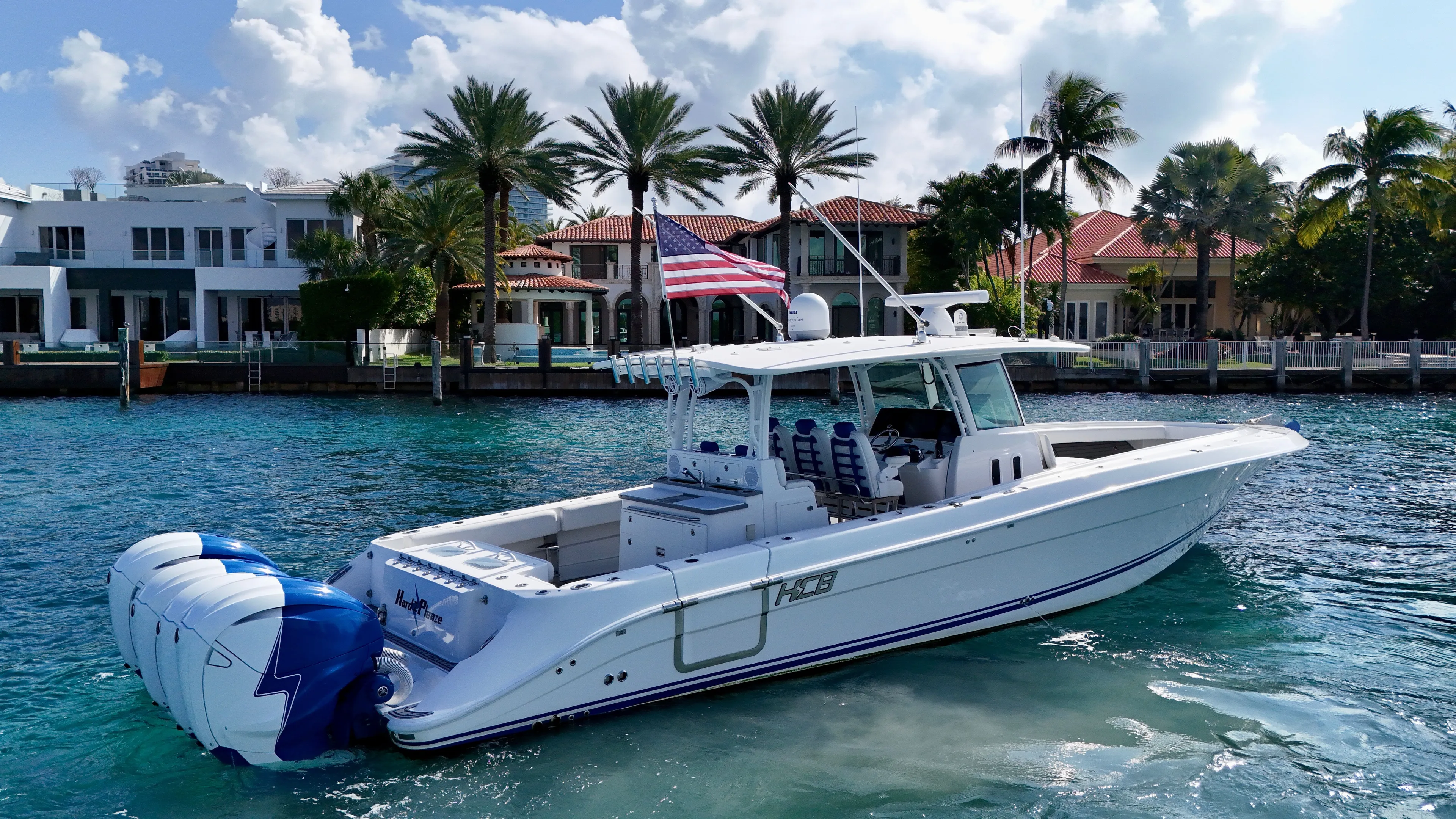  Yacht Photos Pics 2019 HCB 42 Siesta boat on water, American flag, luxury waterfront homes in background.