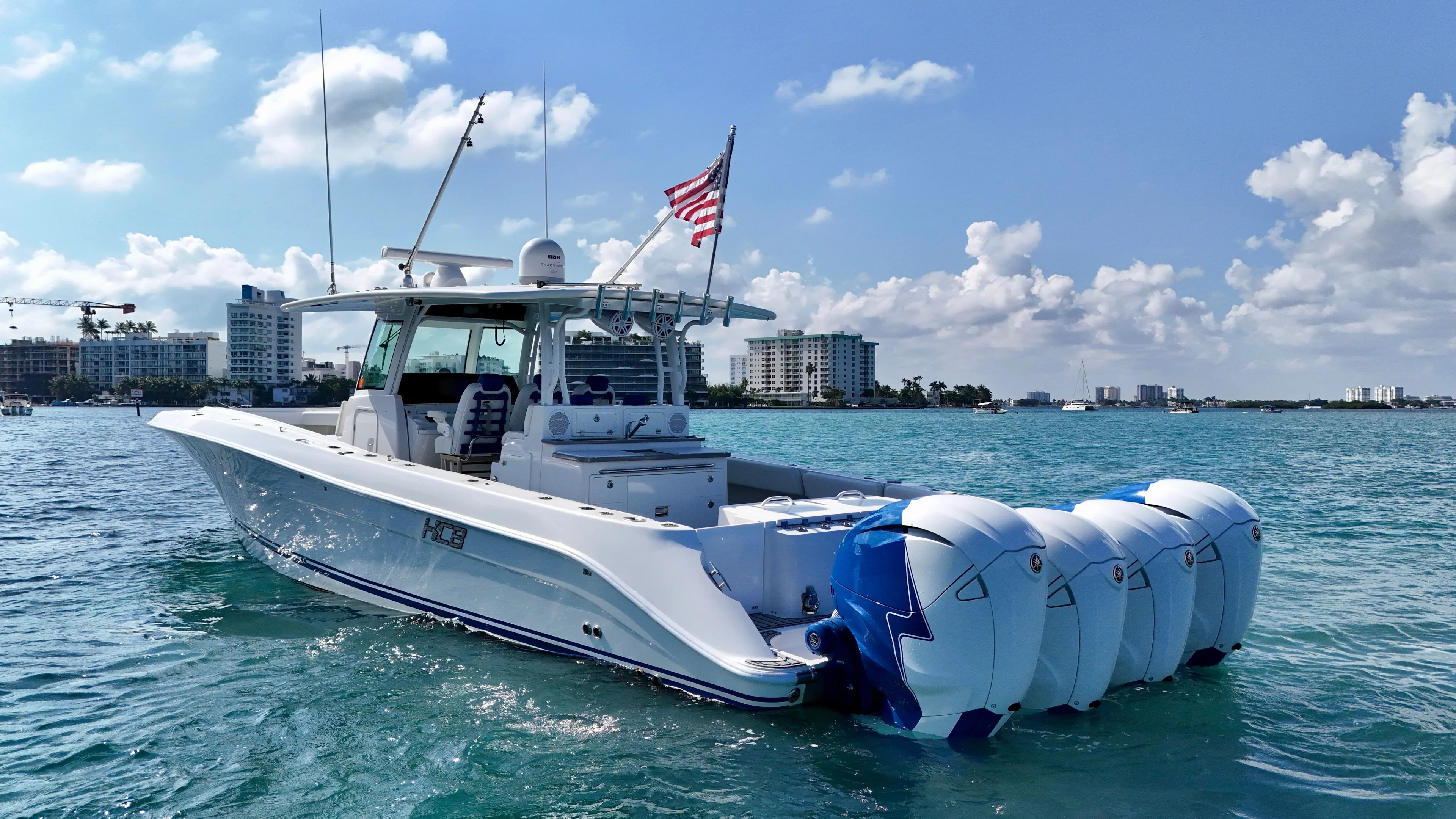  Yacht Photos Pics 2019 HCB 42 Siesta boat on water, city skyline in background, American flag flying.