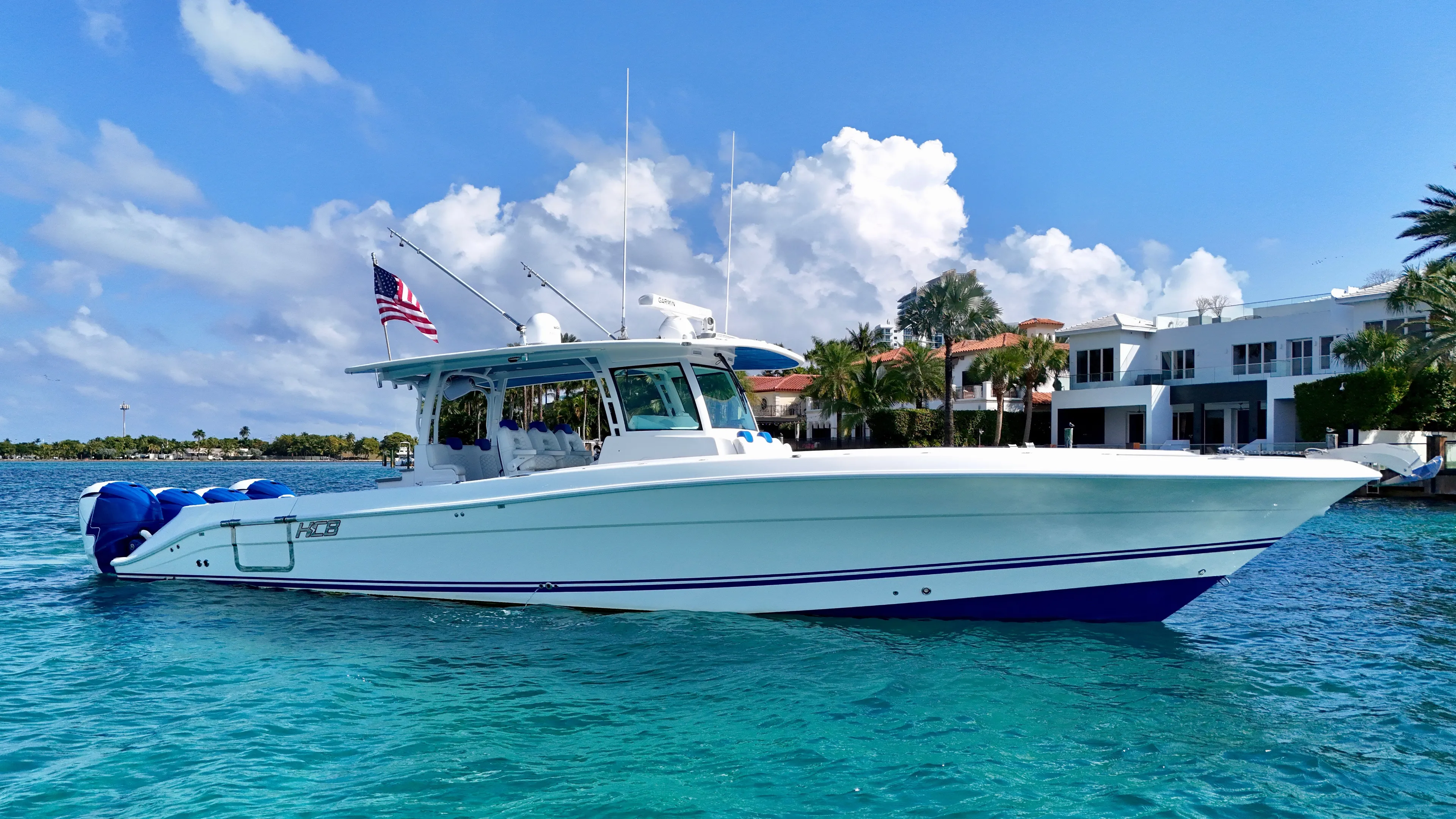  Yacht Photos Pics 2019 HCB 42 Siesta boat cruising on clear blue water near luxury waterfront homes.