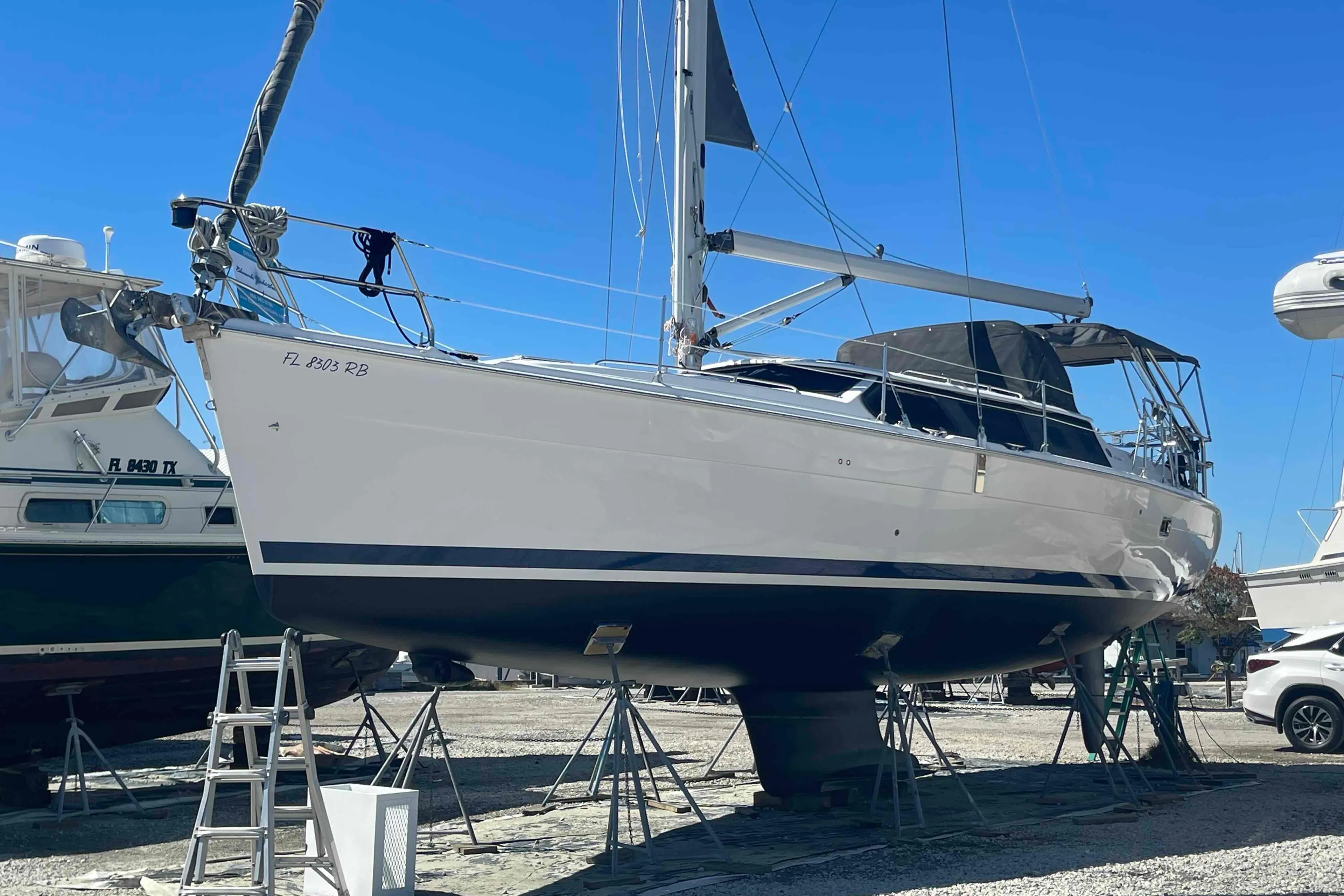 2003 Hunter 426 Deck Salon sailboat on stands, ready for maintenance under clear blue sky.