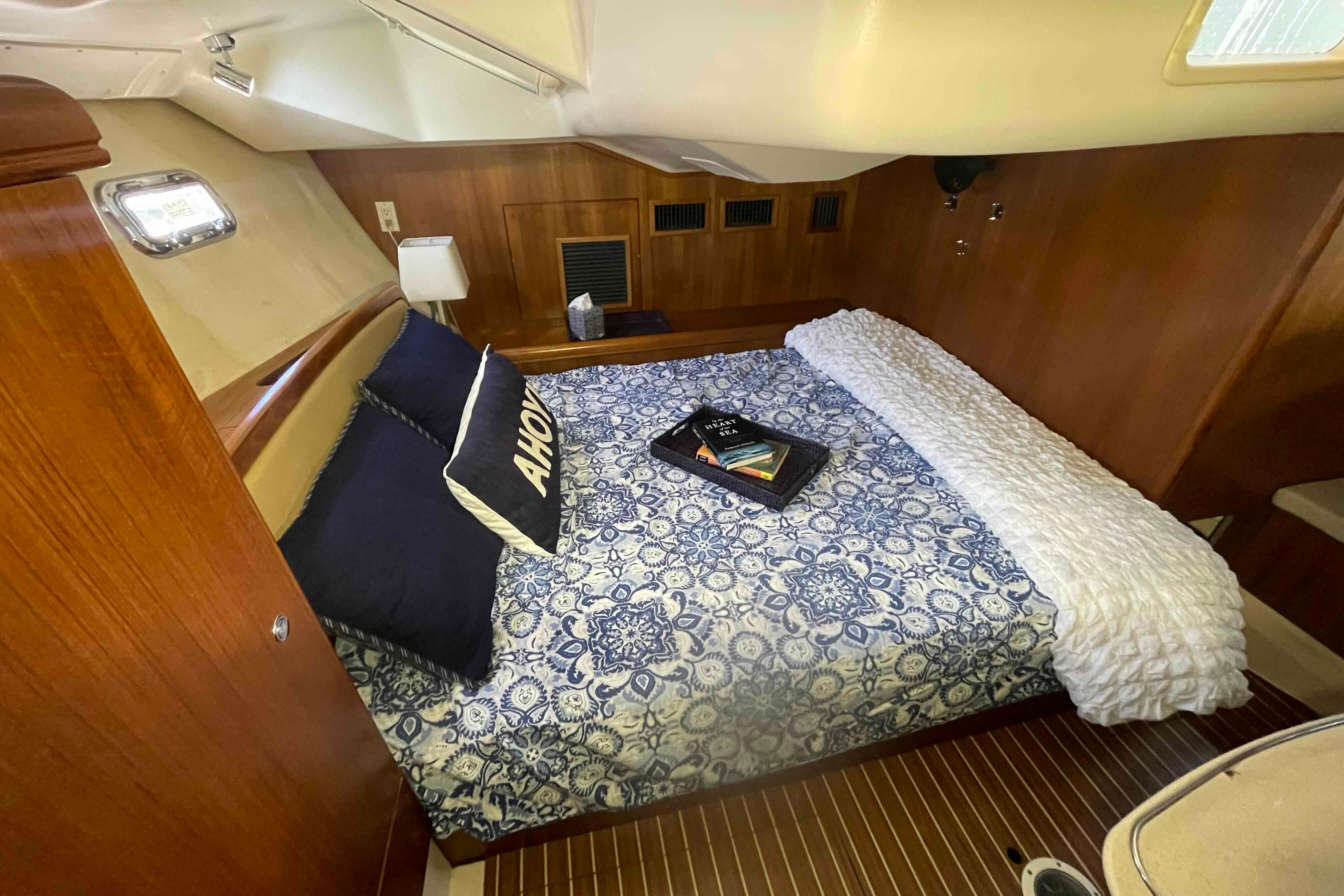 Cozy cabin interior of 2003 Hunter 426 Deck Salon with nautical bedding and wood paneling.