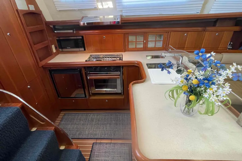 La Veda Yacht Photos Pics Luxurious 2003 Hunter 426 Deck Salon kitchen with wood cabinetry and floral centerpiece.