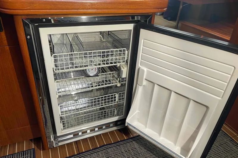 La Veda Yacht Photos Pics Open refrigerator inside 2003 Hunter 426 Deck Salon yacht, featuring wire shelves and wooden cabinetry.