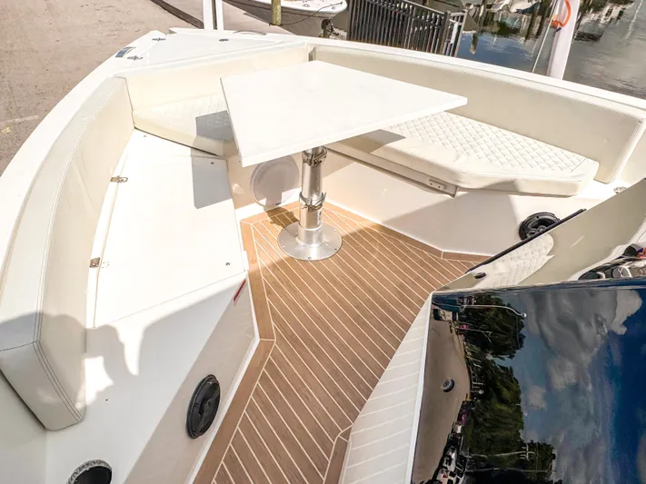  Yacht Photos Pics 2024 De Antonio Yachts D28 Open interior with seating and table, docked by the water.