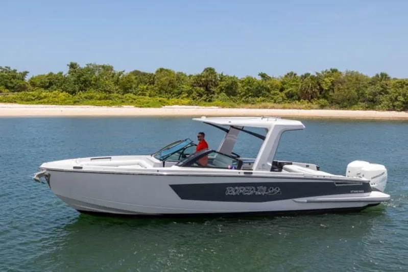  Yacht Photos Pics 2020 Aviara AV32 OB boat cruising on a calm lake near a forested shoreline.