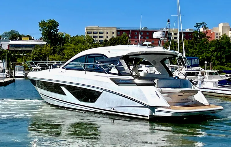 Vamanos Yacht Photos Pics 2023 Beneteau Gran Turismo 41 yacht docked in a marina, surrounded by buildings and trees.