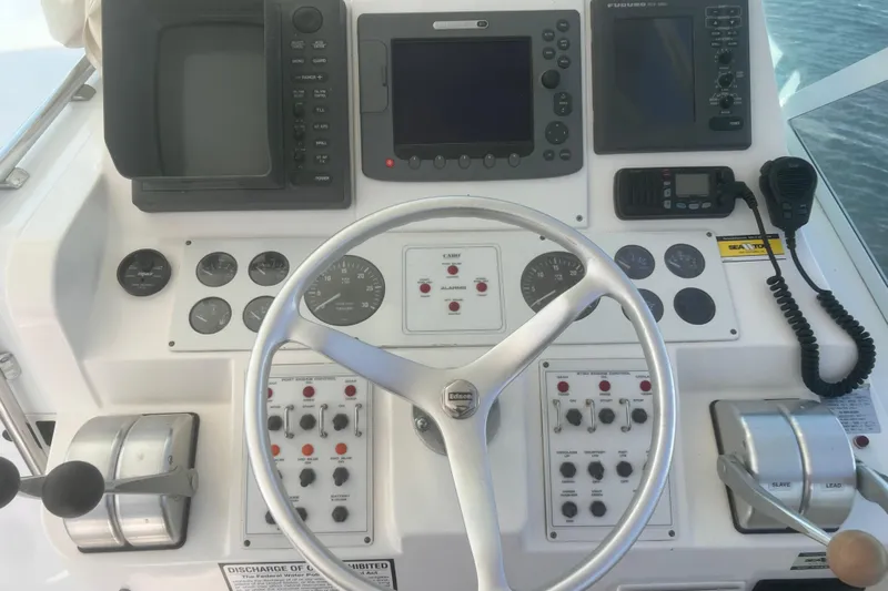 Unreel Yacht Photos Pics Control panel of a 2001 Cabo 31 Express boat with steering wheel and navigation instruments.