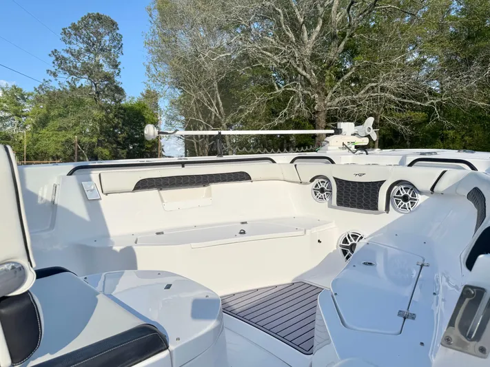  Yacht Photos Pics 2024 Tidewater 292 CC Adventure boat interior with seating and speakers, surrounded by trees.