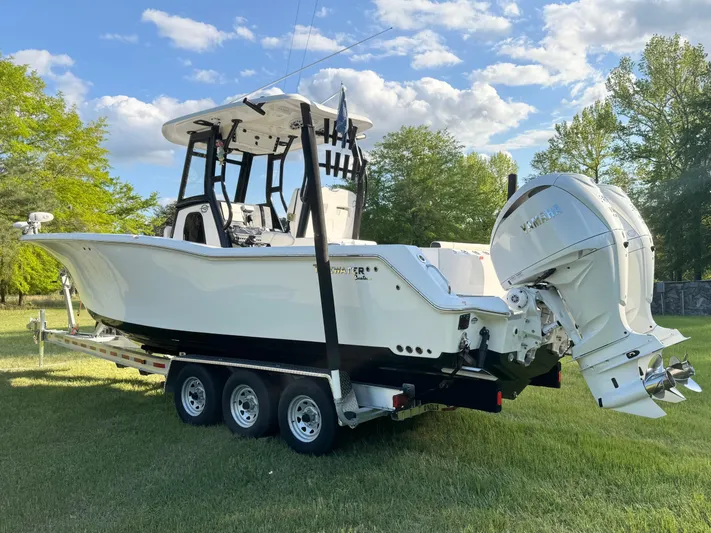  Yacht Photos Pics 2024 Tidewater 292 CC Adventure boat on trailer, parked on grass, under a blue sky.
