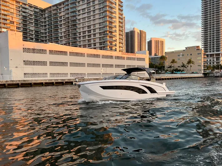  Yacht Photos Pics 2023 Hanover 377 boat cruising near urban waterfront buildings at sunset.