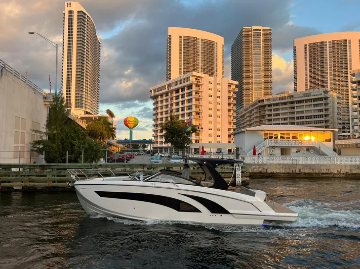  Yacht Photos Pics Modern Hanover 377 boat cruising near urban high-rise buildings at sunset, 2023 model.