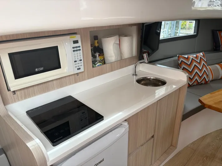  Yacht Photos Pics Modern kitchen in 2023 Hanover 377 boat with microwave, sink, and seating area.