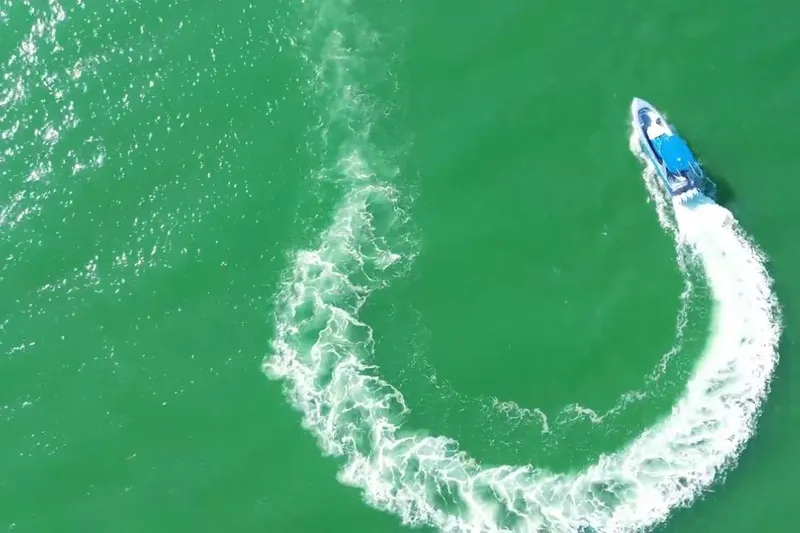Take It To The Max Yacht Photos Pics Aerial view of 2023 Mystic Powerboats M3800 making a sharp turn on green water.