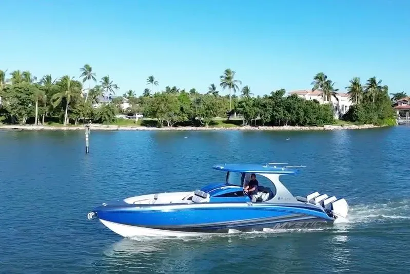 Take It To The Max Yacht Photos Pics 2023 Mystic Powerboats M3800 cruising on a scenic waterway with palm trees in the background.