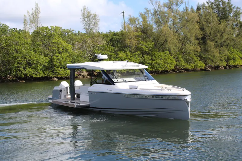  Yacht Photos Pics 2025 Saxdor 400 GTS boat cruising on a serene waterway surrounded by lush greenery.
