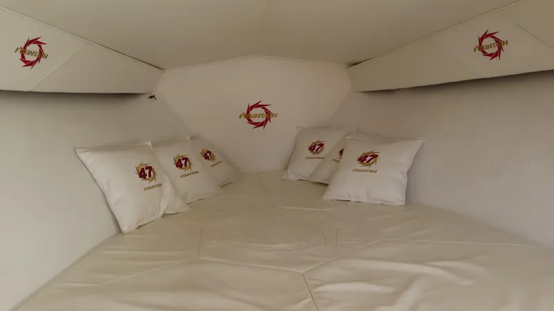  Yacht Photos Pics Interior cabin of 2002 Fountain 47 Lightning boat with branded pillows and white bedding.