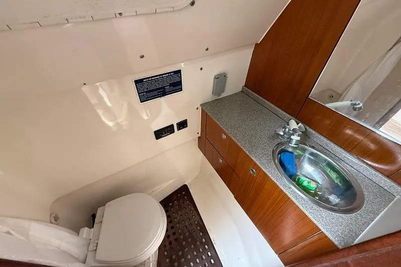  Yacht Photos Pics 2006 Pursuit 345 Drummond Sportfish boat bathroom with sink, toilet, and wooden cabinetry.
