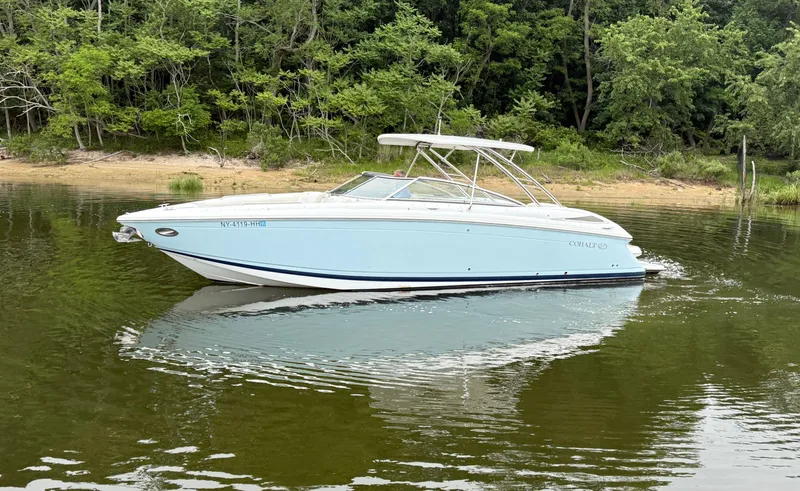  Yacht Photos Pics 2015 Cobalt 302 boat on calm water near a forested shoreline.