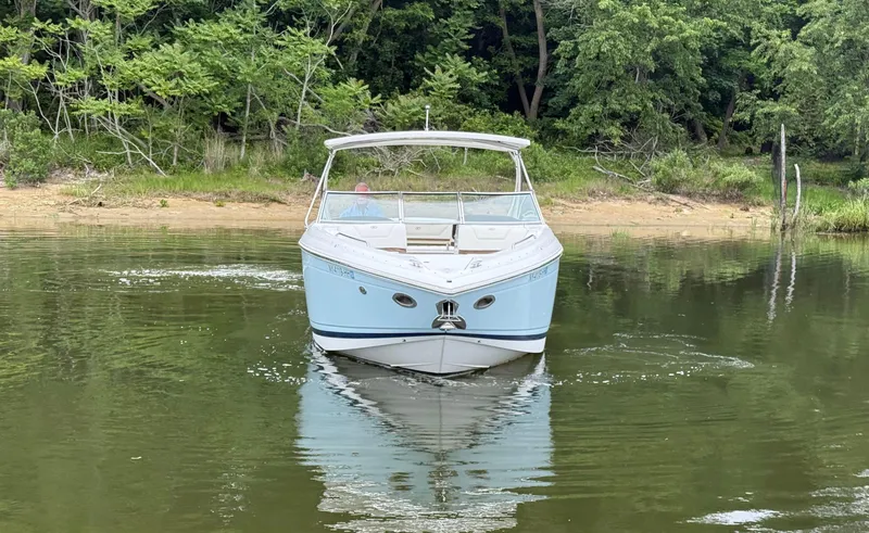  Yacht Photos Pics 2015 Cobalt 302 boat on calm water near a forested shoreline.