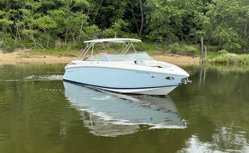  Yacht Photos Pics 2015 Cobalt 302 boat cruising on a calm lake near a forested shoreline.