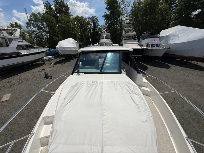  Yacht Photos Pics 2022 Regal 36 XO boat on land, surrounded by trees and other vessels.