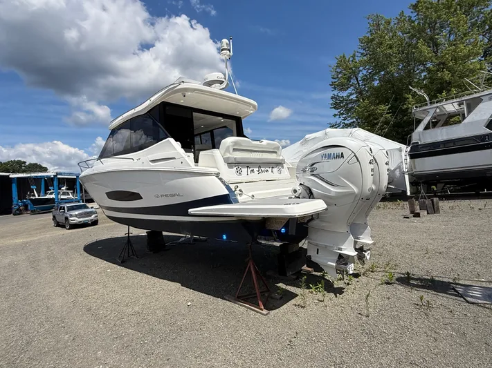  Yacht Photos Pics 2022 Regal 36 XO boat with Yamaha engines on a gravel lot under a blue sky.