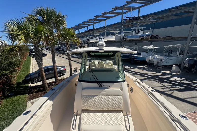 Your New Boat! Yacht Photos Pics 2024 Grady-White Canyon 336 boat docked near palm trees and parked cars.