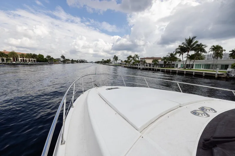 Sea Diva Yacht Photos Pics 1999 Azimut 58 yacht cruising on a scenic waterway with palm trees and cloudy sky.