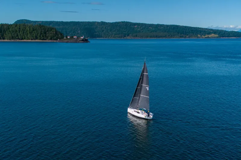 "mah Na Mah Na" Yacht Photos Pics Sailboat J/112E 2020 cruising on blue waters near forested island.